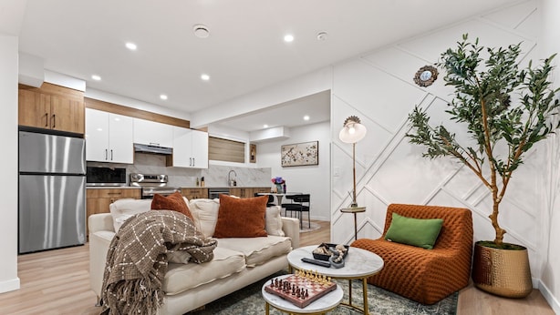 A modern living room with a sofa, coffee table, and a chessboard. - 2BR Near YEG Airport | King Bed + Mini Golf! (Nisku)