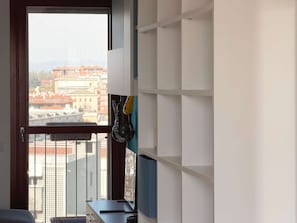 A room with a window, a desk, and a wall with shelves. - Loft Pitteri Relaxing With Panorama (Milan)