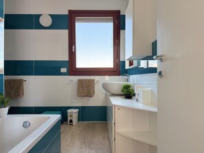 Ein modernes Badezimmer mit Badewanne, Waschbecken und Fenster.
