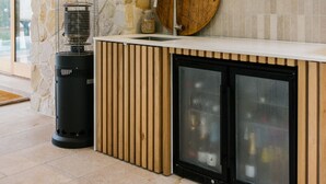 A modern kitchen with a stone wall, a wooden barrel, a built-in sink, and a glass-fronted refrigerator.