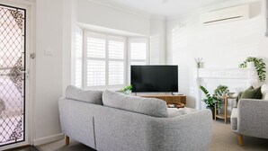 Un salon avec un canapé gris, un téléviseur à écran plat et une cheminée.