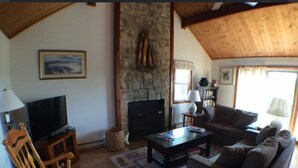 Ein Wohnzimmer mit Fernseher, Kamin, Sofa und Couchtisch.