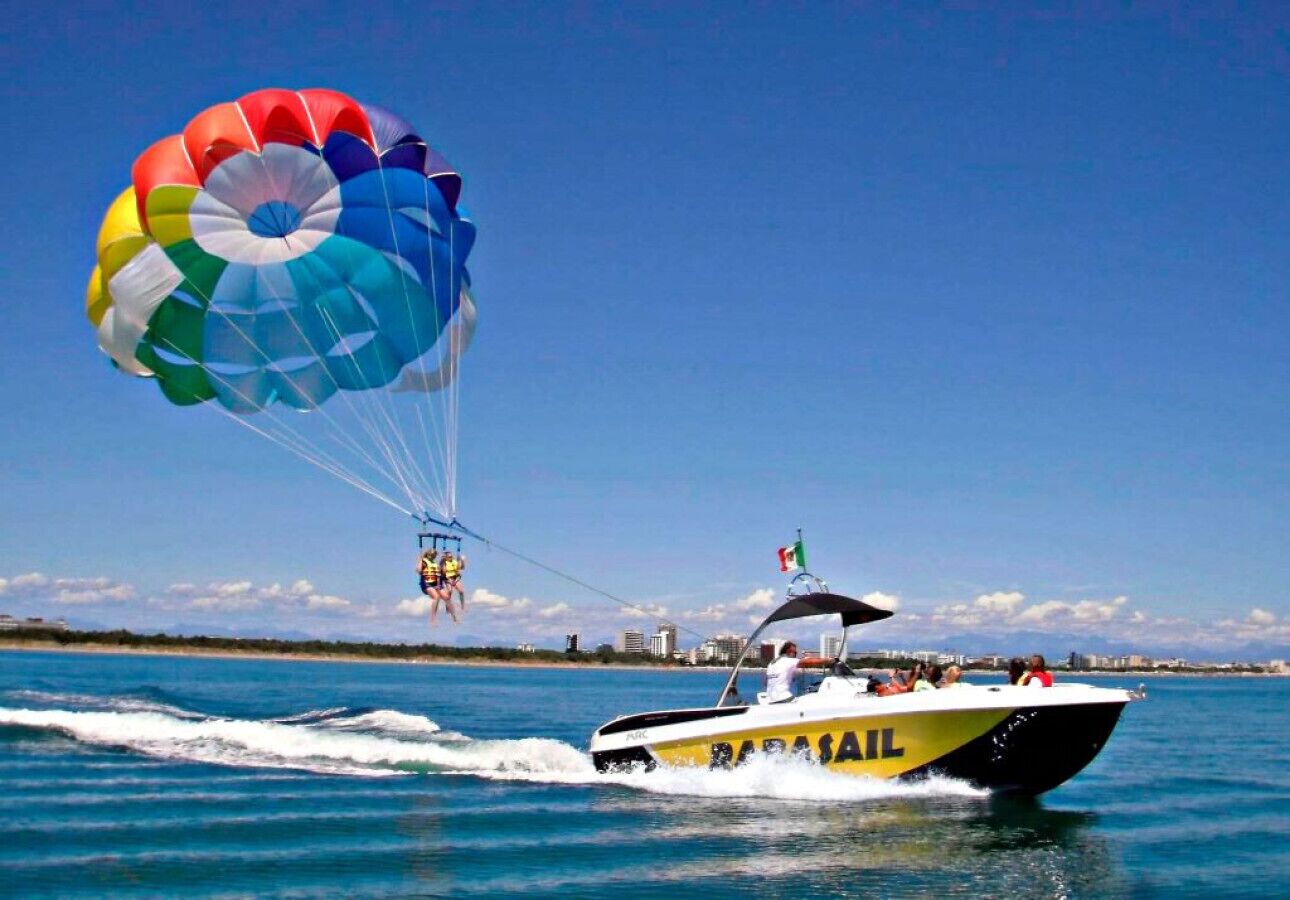Ein Parasail mit mehreren Personen, gezogen von einem Schnellboot mit der Aufschrift 'PARASAIL'.