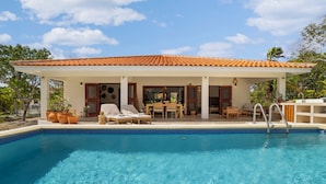 Un espace aménagé au bord de la piscine, avec une piscine carrelée, des chaises longues et un coin salon abrité.