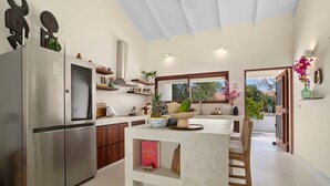 Una cocina moderna con una isla central, electrodomésticos de acero inoxidable y vistas al exterior.