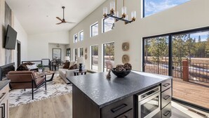 A spacious living area with a large island, a ceiling fan, and a view of the outdoors. - Hilltop Luxury with Terry Peak Views, Resort Amenities & Year-Round Pool (Lead)
