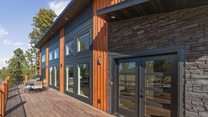 A modern building with a wooden deck, large windows, and stone facade. - Hilltop Luxury with Terry Peak Views, Resort Amenities & Year-Round Pool (Lead)