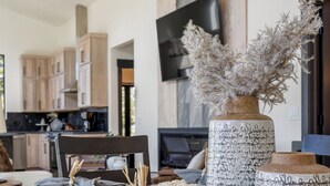 A dining table with placemats, a vase with dried plants, and a television in the background. - Hilltop Luxury with Terry Peak Views, Resort Amenities & Year-Round Pool (Lead)