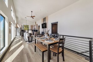 Una cocina moderna con armarios de madera, un comedor con una mesa dispuesta para cuatro personas y un amplio ventanal que proporciona luz natural.