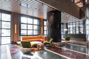 A lobby with a large black column, a sofa, and chairs. - Queensbridge Luxe River Suite. Heated Pool, Gym, Sauna, Steam, Bar, beside Crown (Southbank)