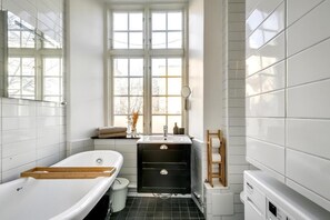 A bathroom with a bathtub, a sink, and a window. - Central 3-bedroom apartment next to the Royal Palace and the Old Town (Stockholm)