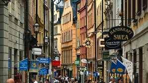 A busy street with shops and signs, including 'Handkraft Sweden' and 'Money Change'. - 3BR in Gamla Stan by the Royal Palace (Stockholm)