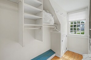 Ein Zimmer mit Einbauschrank, Fenster mit Jalousien und Holzboden.