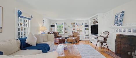 Una sala de estar con sofá, mesa de centro, chimenea y televisor.