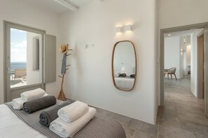 Ein Schlafzimmer mit Bett, Handtüchern, einem Spiegel und Meerblick.