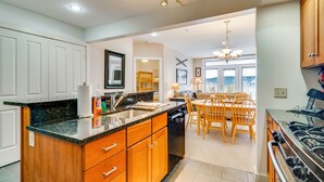 A kitchen with wooden cabinets, a granite countertop, a dishwasher, and a dining area with wooden chairs and a table. - Direct Trail Access: Resort-style Killington Gem (Killington)