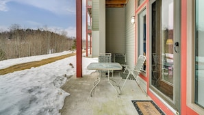 A covered porch with a table and chairs, a wooden ceiling, and a view of a snowy landscape. - Direct Trail Access: Resort-style Killington Gem (Killington)