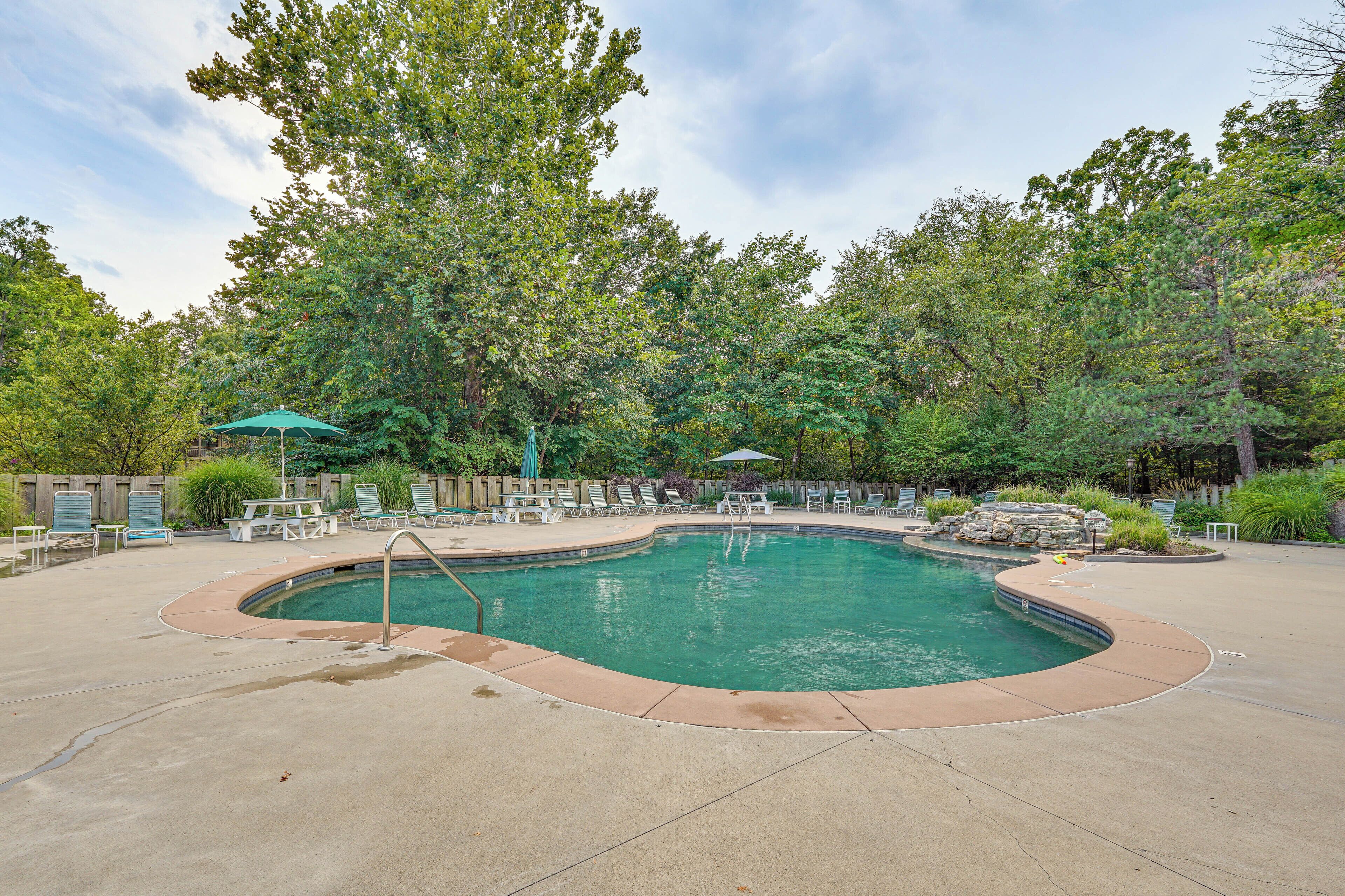 A swimming pool with a curved edge, surrounded by lounge chairs and umbrellas.