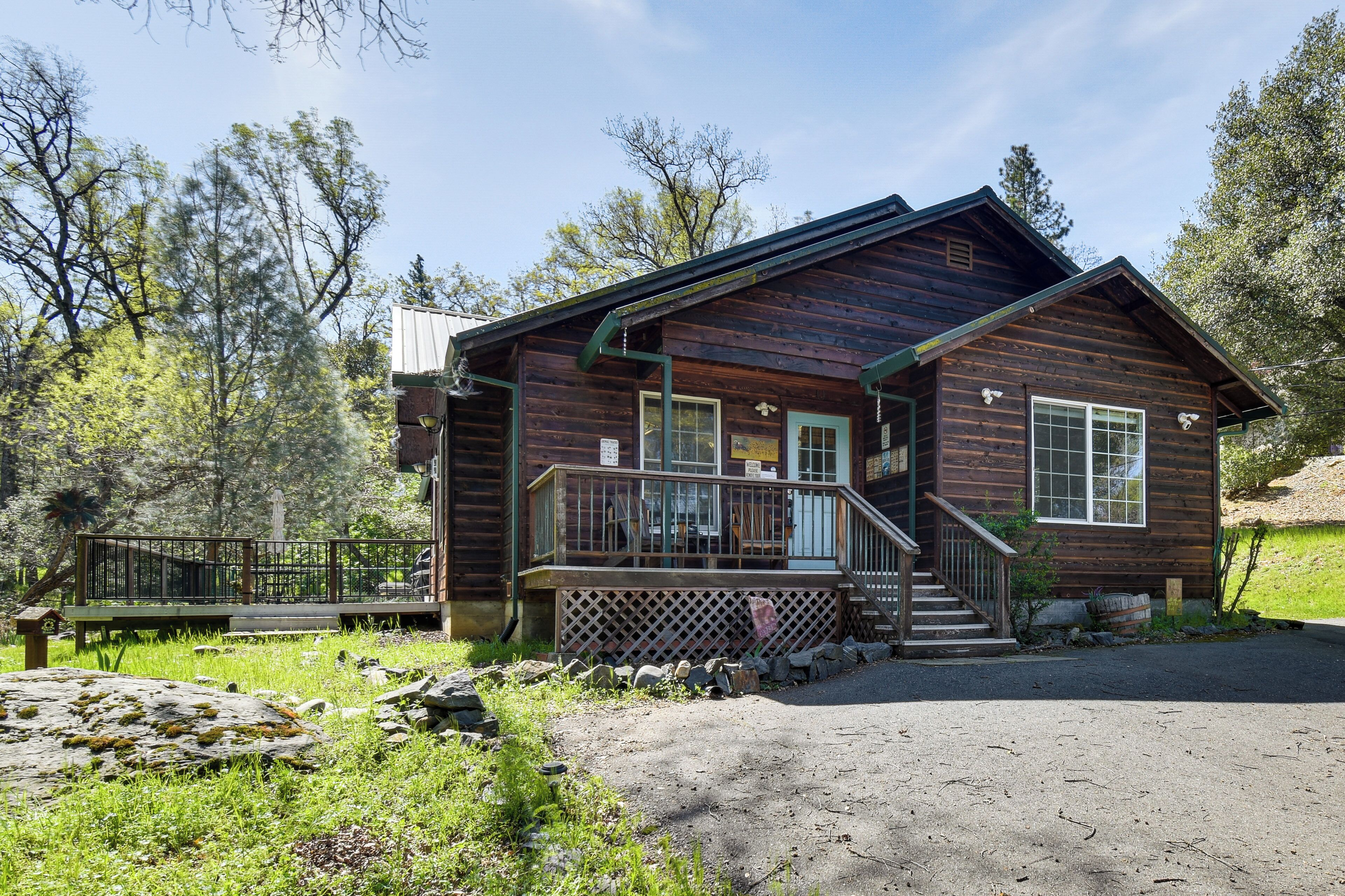 A wooden cabin with a porch, a staircase, and a fenced area.