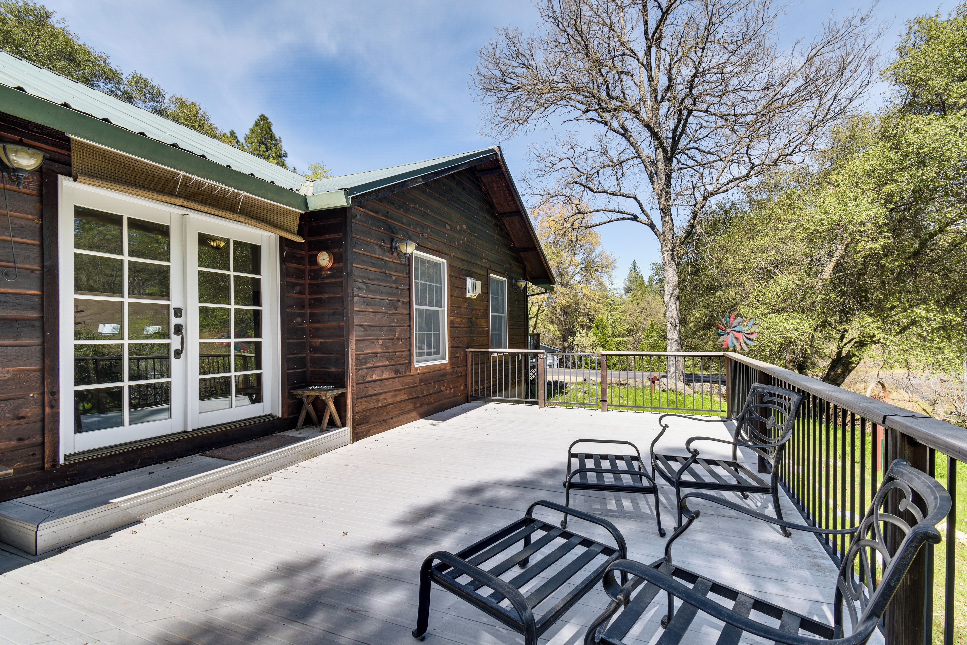 Eine Holzhütte mit einer Terrasse, einer Veranda und einem eingezäunten Garten.