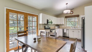 A kitchen with white cabinets, a wooden dining table, and a view through the window. - Swim & Golf! 'jackson Mill Cottage' in Groveland (Groveland)