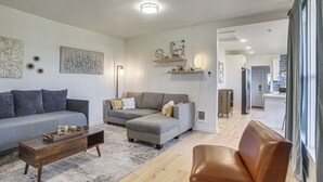 Un salon moderne avec un canapé, un fauteuil en cuir, une table basse et un tapis.