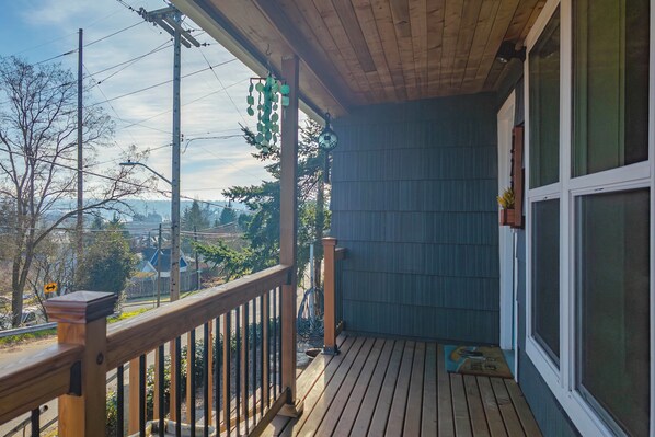 A wooden deck with a railing, a clock, and a window.