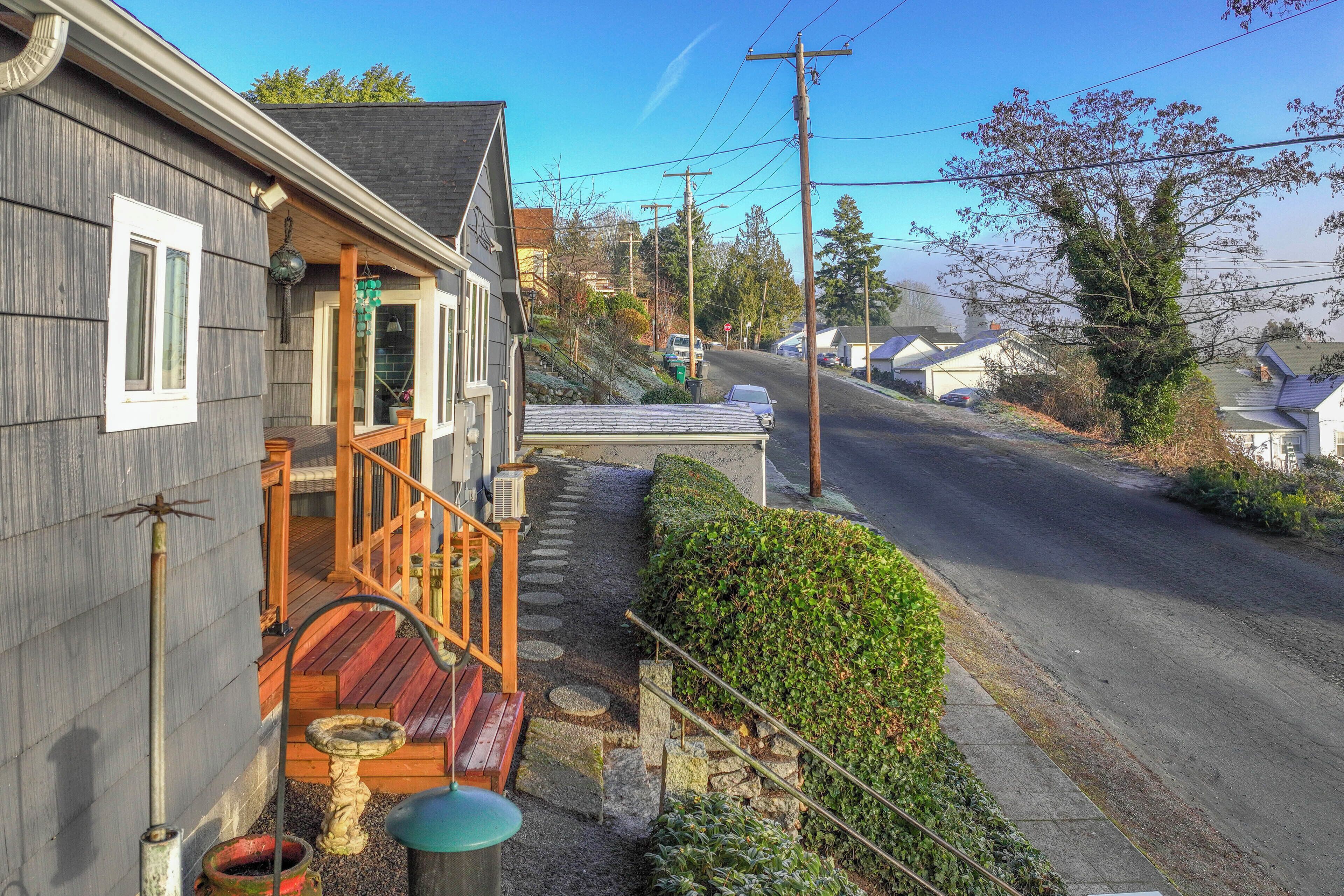A residential property with a wooden deck, a stone pathway, and a clear view of the street.