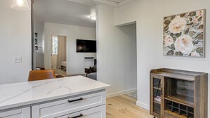 Une cuisine moderne avec des meubles blancs, un plan de travail en marbre et un meuble en bois doté de portes en verre.