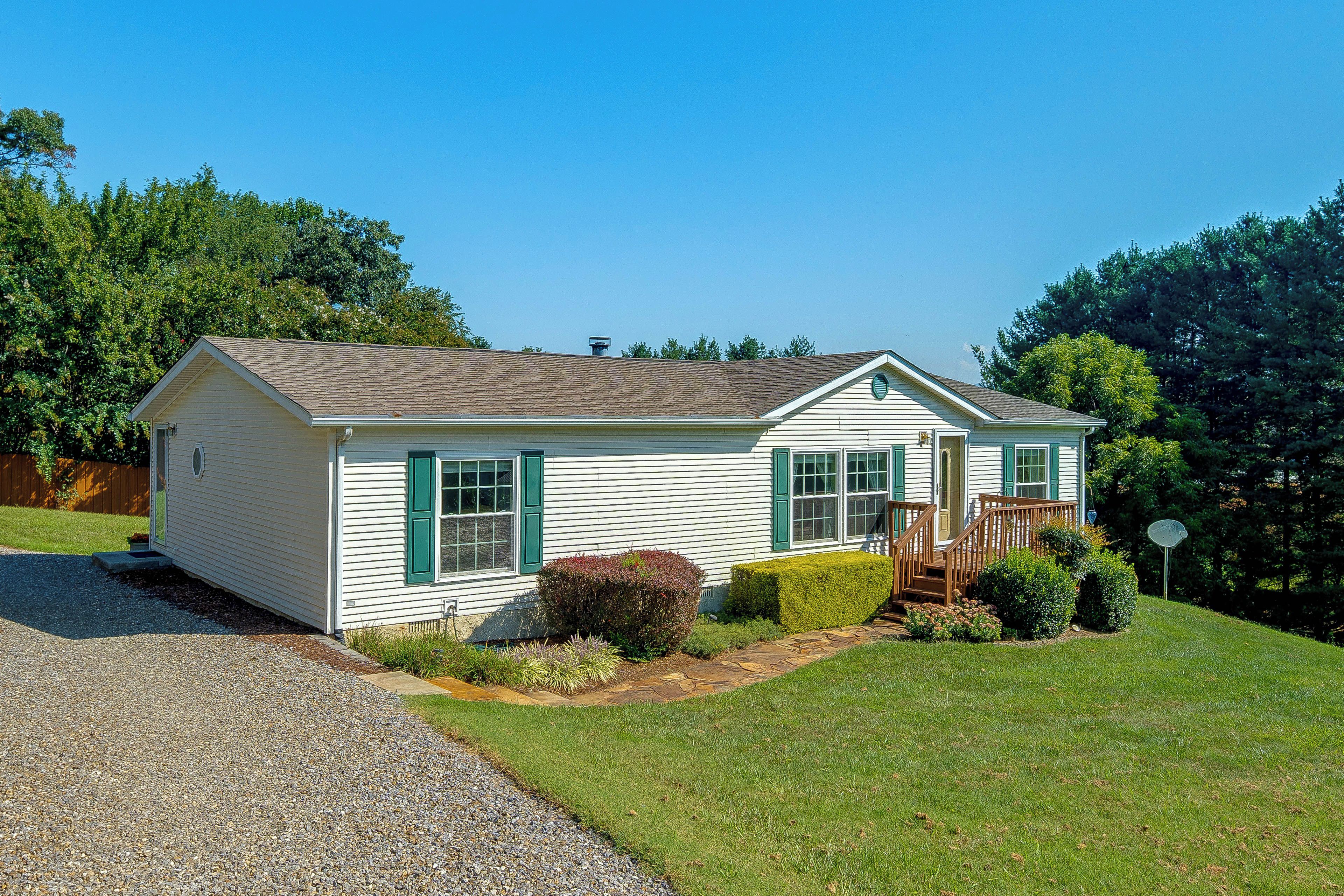 A single-story house with a front porch, a small front yard, and a gravel driveway.