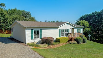 A single-story house with a front porch, a small front yard, and a gravel driveway.