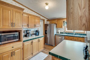 A kitchen with wooden cabinets, a stainless steel refrigerator, a microwave, and a coffee maker. - Long-range Mtn Views! Scenic Asheville Sanctuary (Asheville)