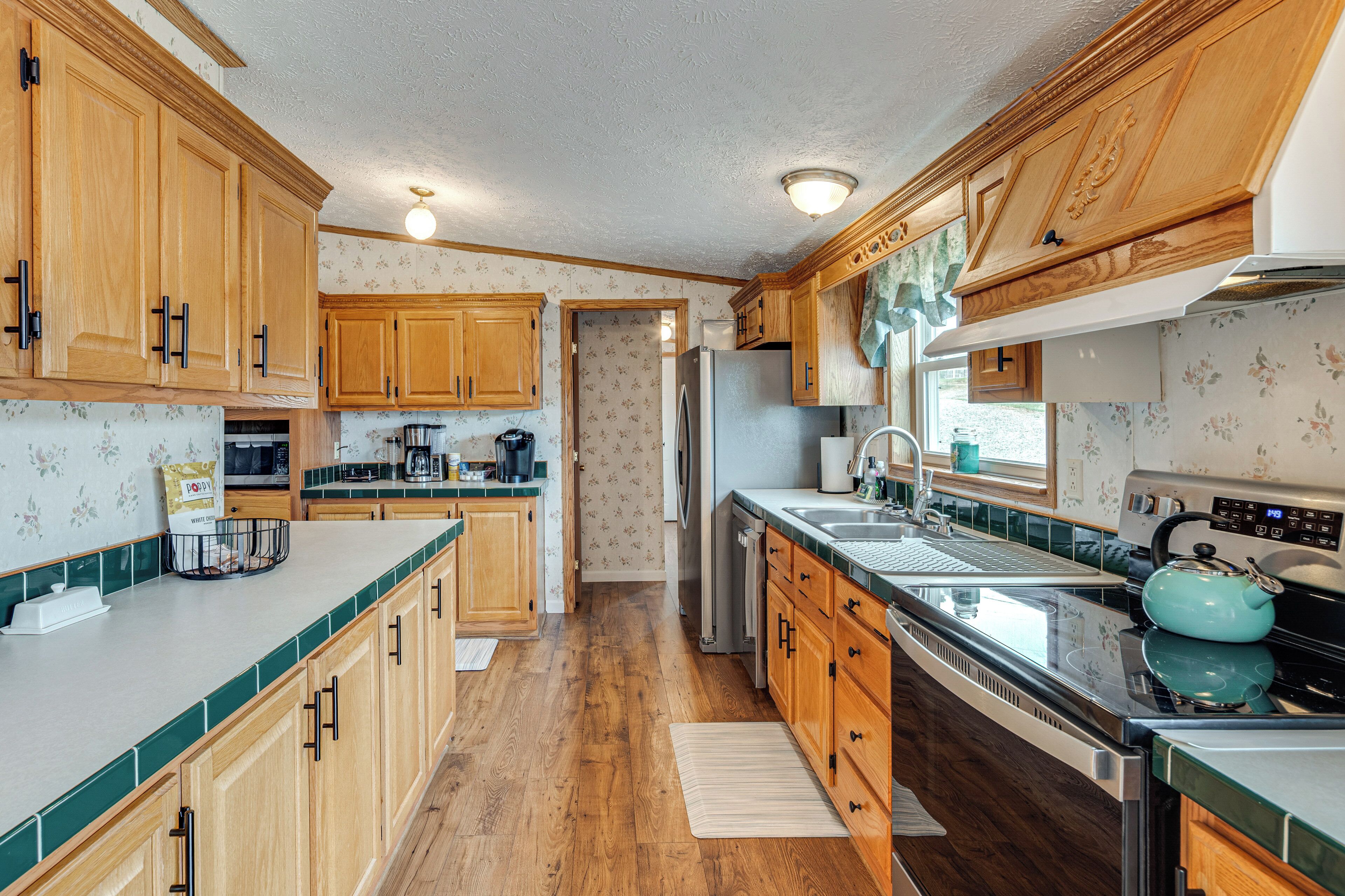 A kitchen with wooden cabinets, a stainless steel refrigerator, and a blue kettle.