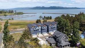 A residential area with a large house featuring a garage, a driveway, and a view of a lake and mountains. - Walk to Marina! River-view Retreat in Hammond (Hammond)