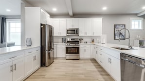 A modern kitchen with white cabinets, stainless steel appliances, and a herringbone wood floor. - Walk to Marina! River-view Retreat in Hammond (Hammond)