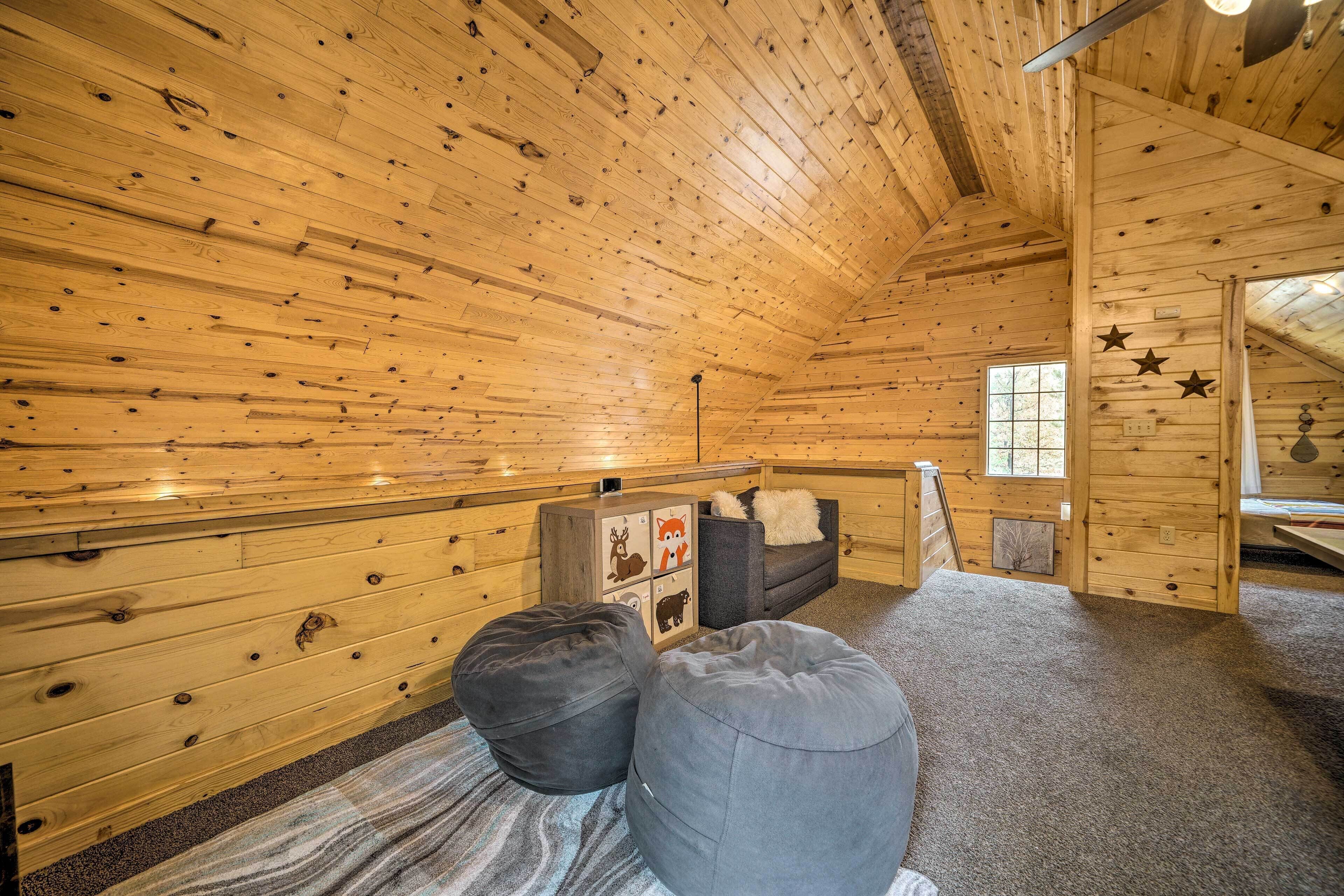 Interior d'una cabana de fusta amb parets de fusta, un sofà, dos seients de bosses i una finestra petita.