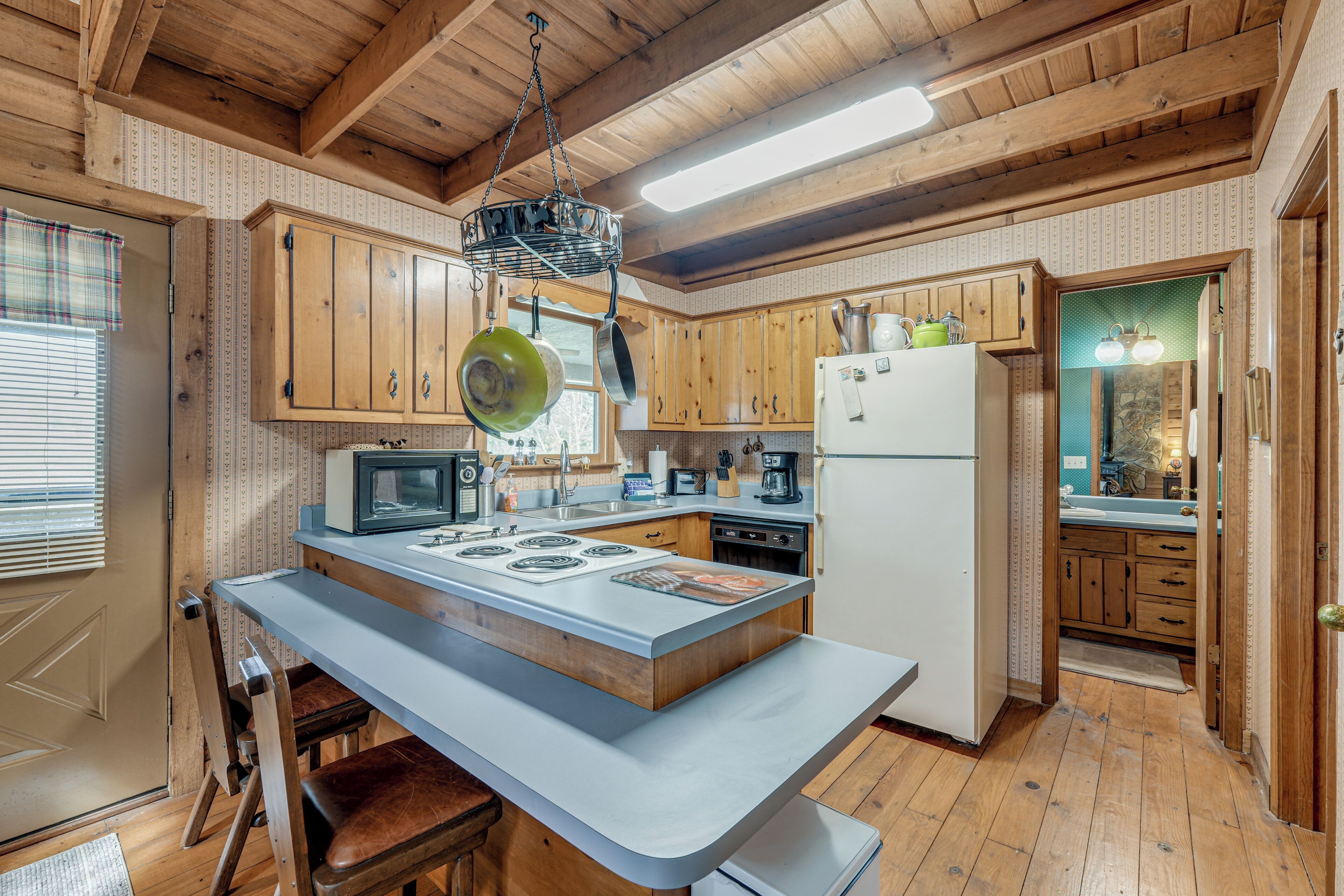 A kitchen with wooden cabinets, a central island, a microwave, a stove, and a refrigerator.