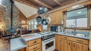 Une cuisine avec des meubles de rangement en bois, une cuisinière et des casseroles suspendues.