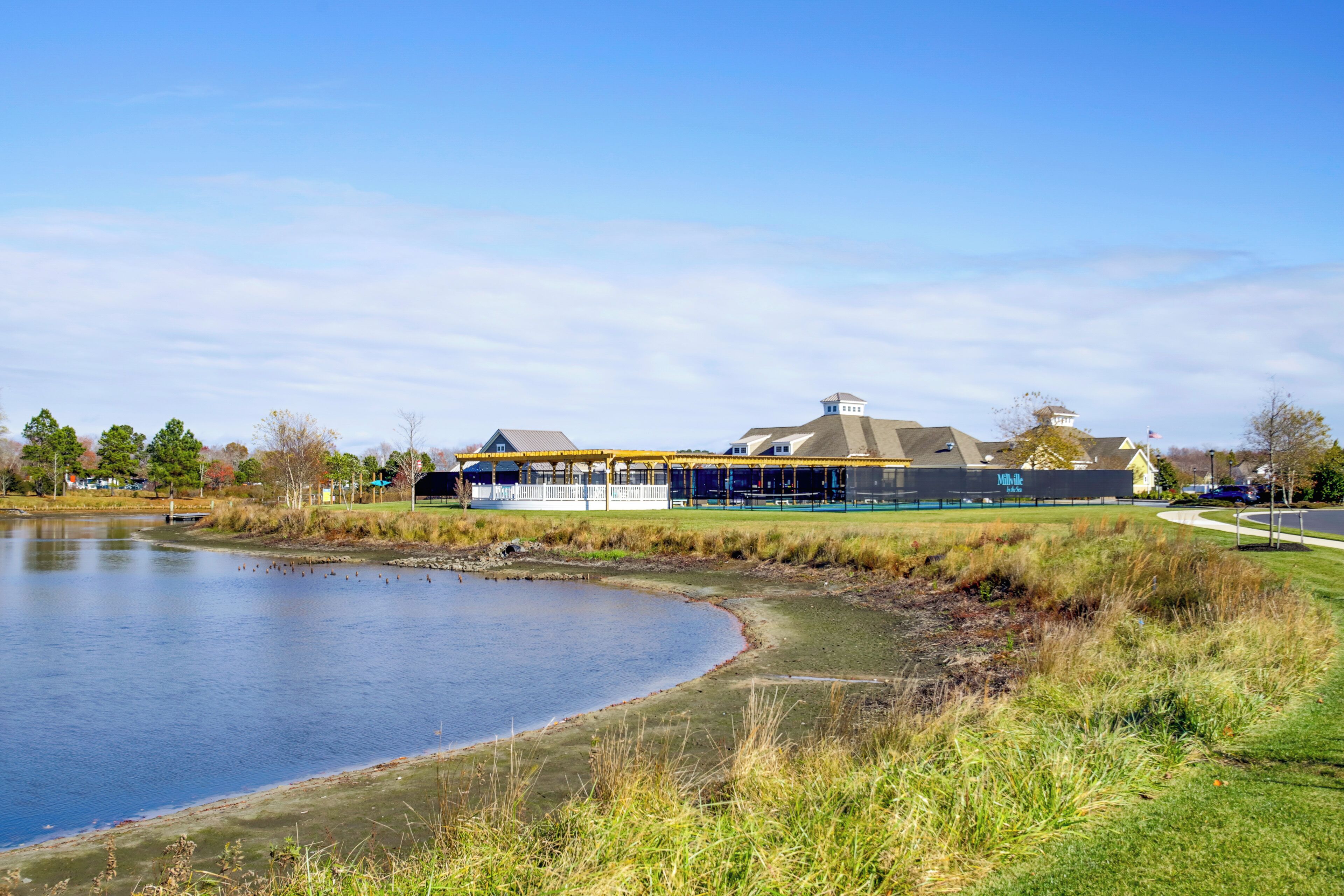 A lakeside view of a building with a covered outdoor area and a parking lot.
