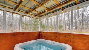 A hot tub in a wooden cabin with large windows and a view of a forest. - Family-ready Efland Home w/ Hot Tub + Deck (Efland)