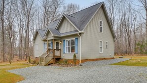 A two-story house with a front porch, a staircase, and a gravel driveway. - Family-ready Efland Home w/ Hot Tub + Deck (Efland)