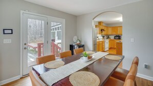A dining area with a table, chairs, and a view of the kitchen. - Family-ready Efland Home w/ Hot Tub + Deck (Efland)