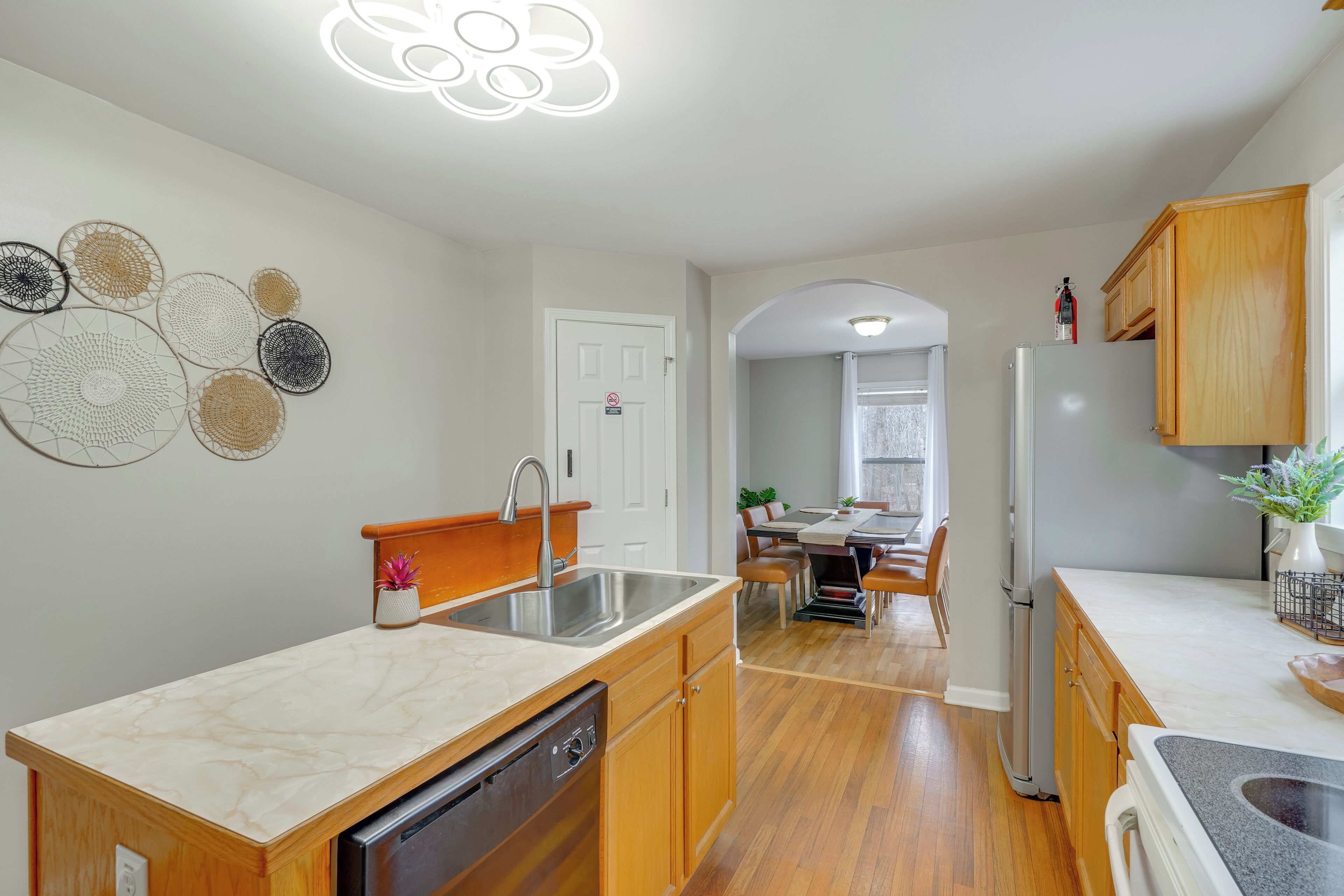Una cocina moderna con lavavajillas, un lavabo, armarios de madera y un comedor con mesa y sillas.