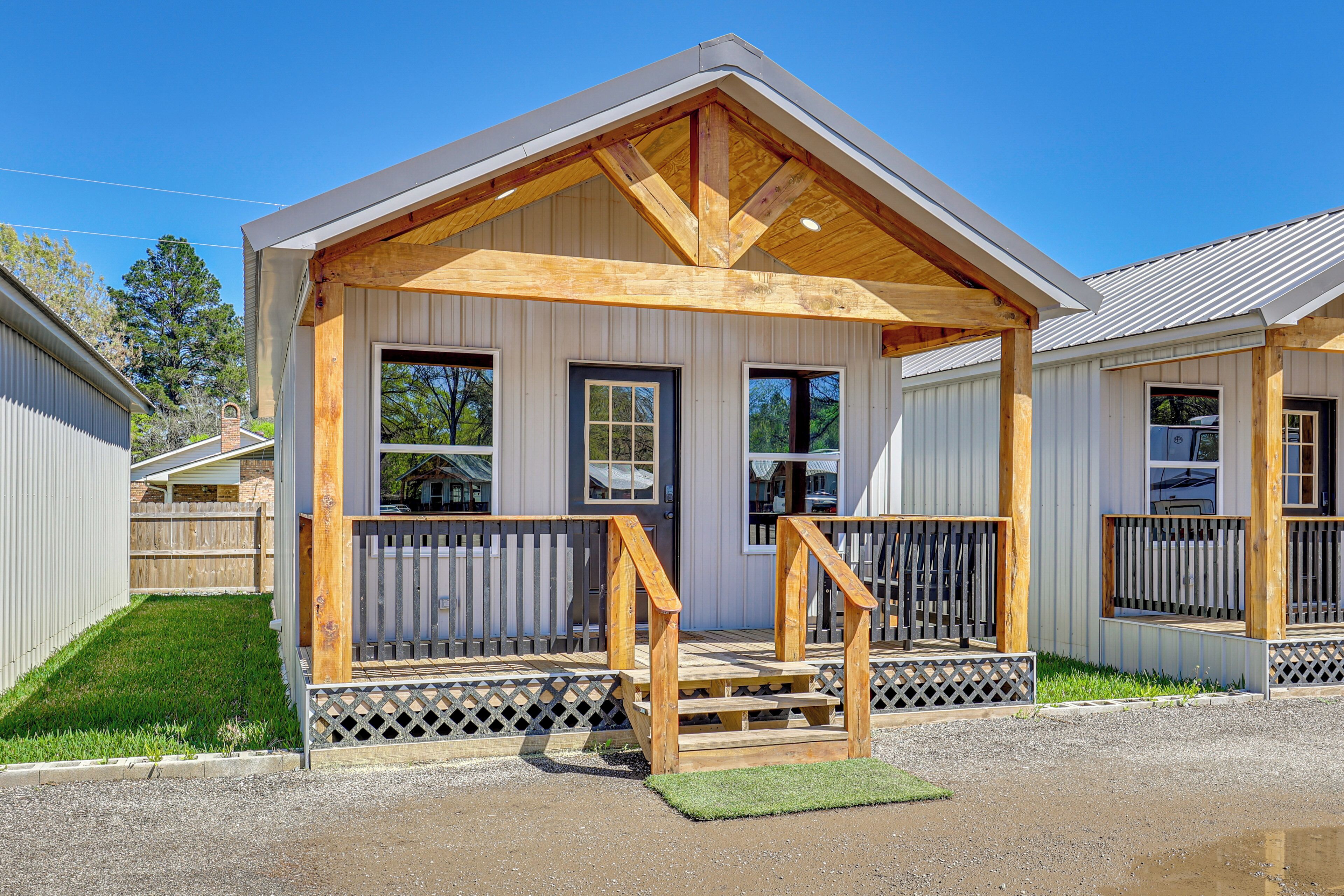 A small, single-story building with a wooden porch, a door, and windows.