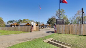 A gated entrance to a property with a flag, wooden fences, and a sign indicating 'SABINE RIVER RETREATS.' - 3 Mi to Boat Ramp! Tiny Cabin Near Sabine River (Joaquin)