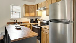 A modern kitchen with wooden cabinets, stainless steel appliances, and a large island with a bowl. - 3 Mi to Boat Ramp! Tiny Cabin Near Sabine River (Joaquin)