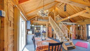 A wooden interior with a dining table, chairs, a chandelier, and a staircase. - Private Hot Tub! Country Retreat in West Virginia (Friendly)