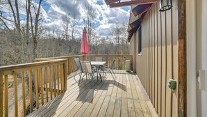 A wooden deck with a table and chairs, a red umbrella, and a lantern. - Private Hot Tub! Country Retreat in West Virginia (Friendly)