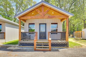 A wooden cabin with a porch, a front door, and a small window. - Boating & Fishing Home Base Near the Sabine River! (Joaquin)