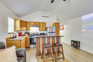 A modern kitchen with wooden cabinets, a stainless steel refrigerator, and a bar area with stools. - Boating & Fishing Home Base Near the Sabine River! (Joaquin)